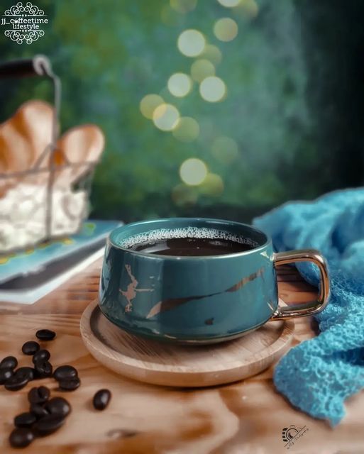 Teal ceramic cup with a gold-toned handle on a wooden plate