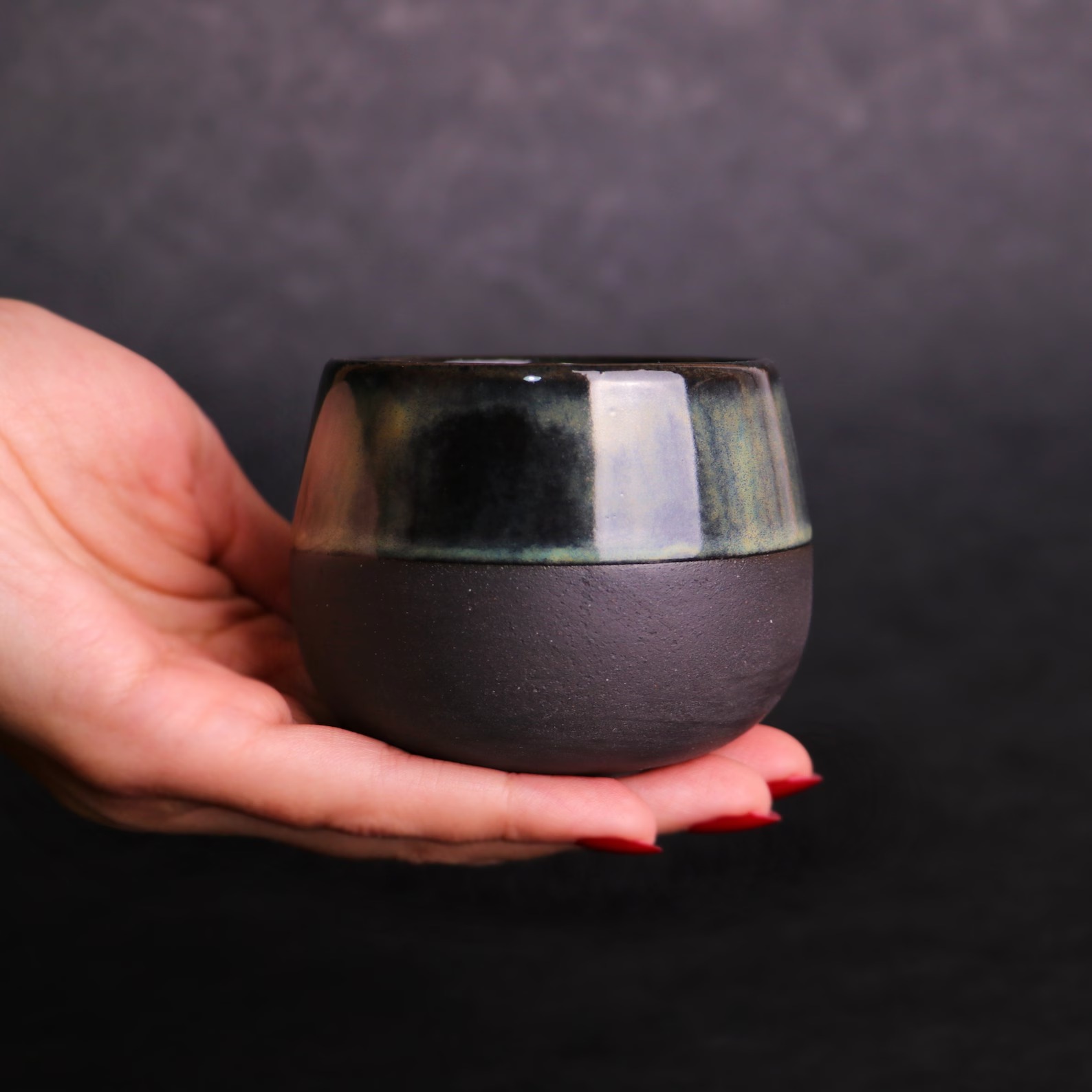 Small handleless ceramic espresso cup with a dark glaze
