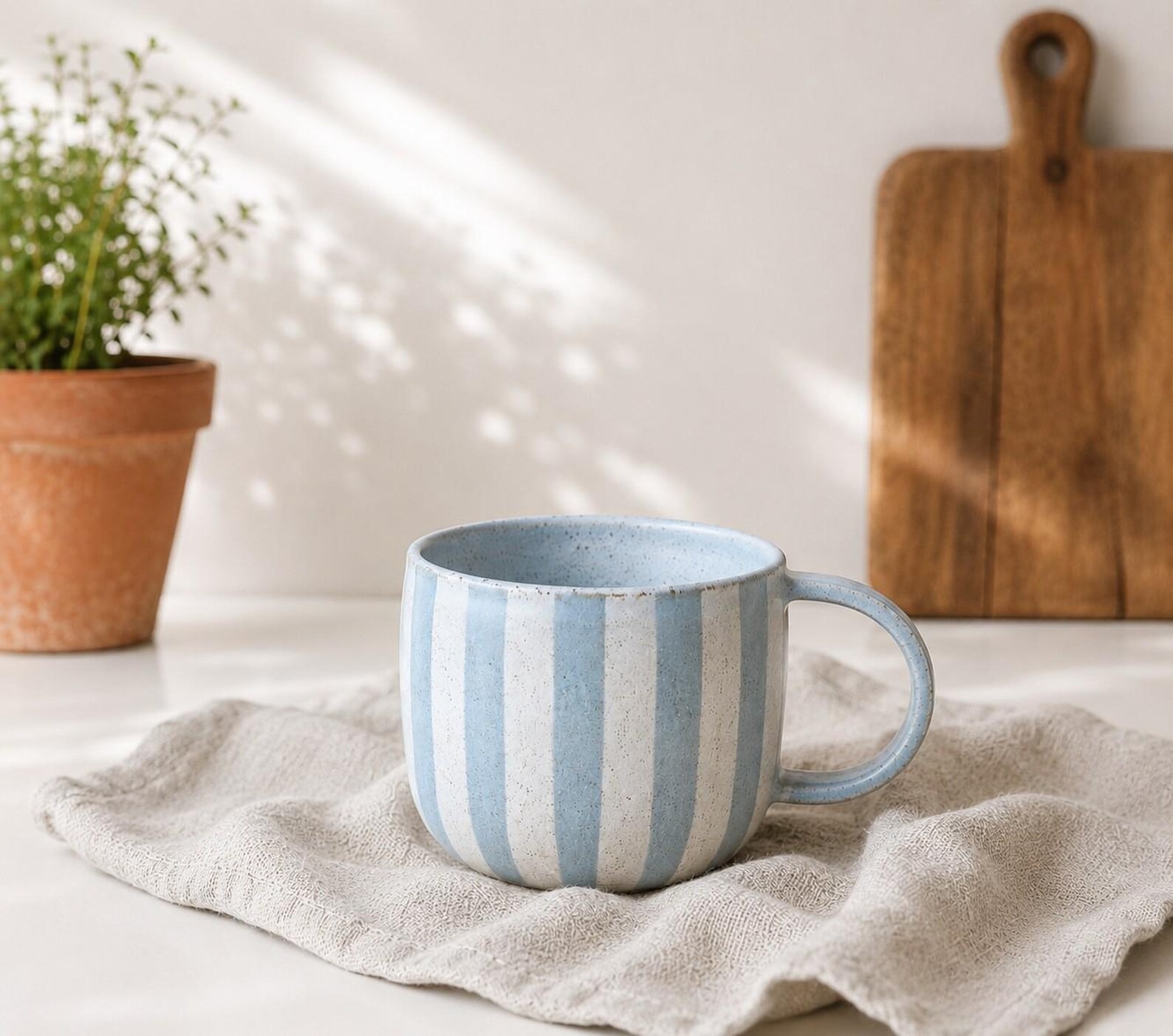 Blue and white striped ceramic mug on a linen cloth