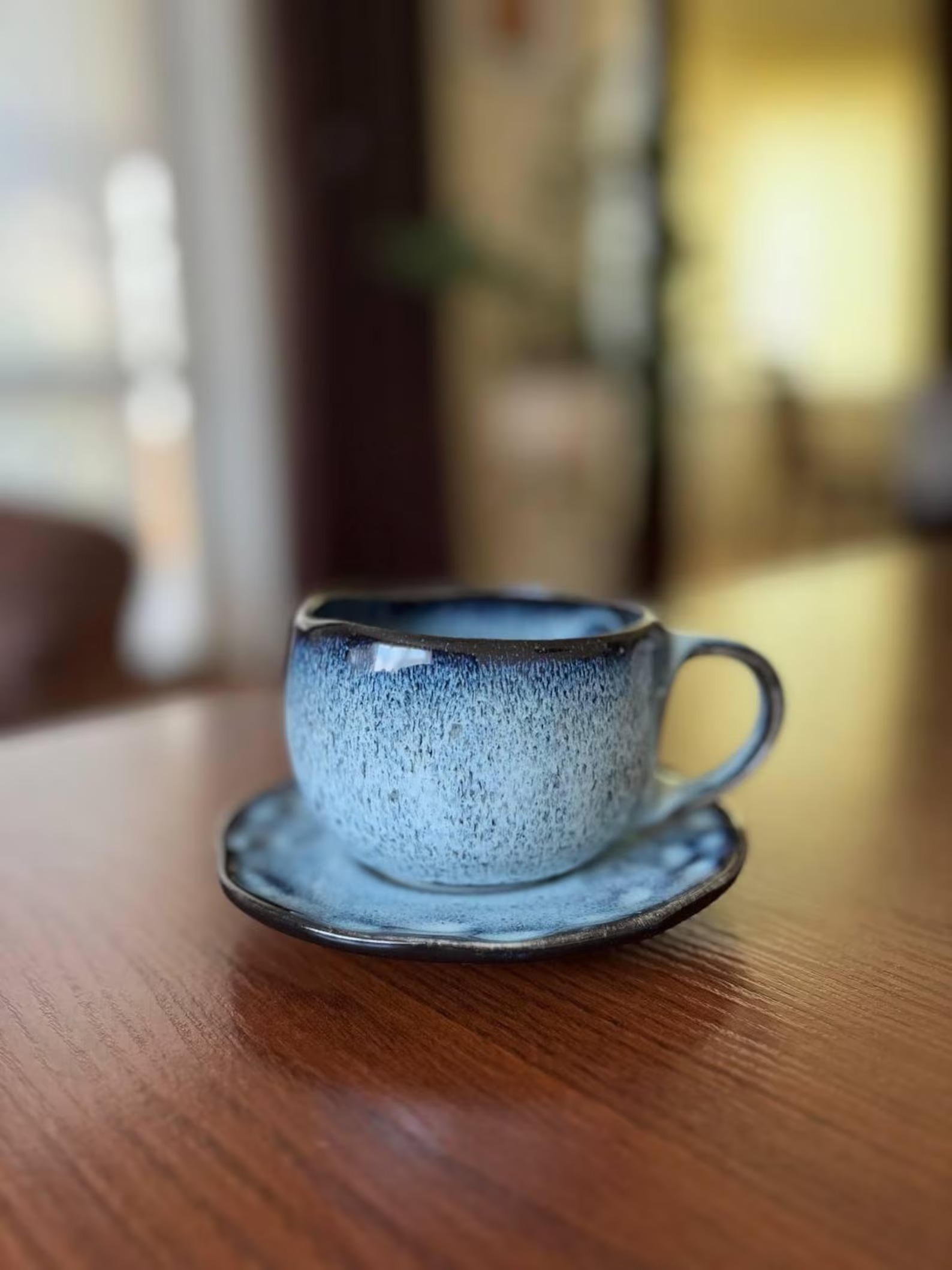 Ceramic cup and saucer set with a blue reactive glaze
